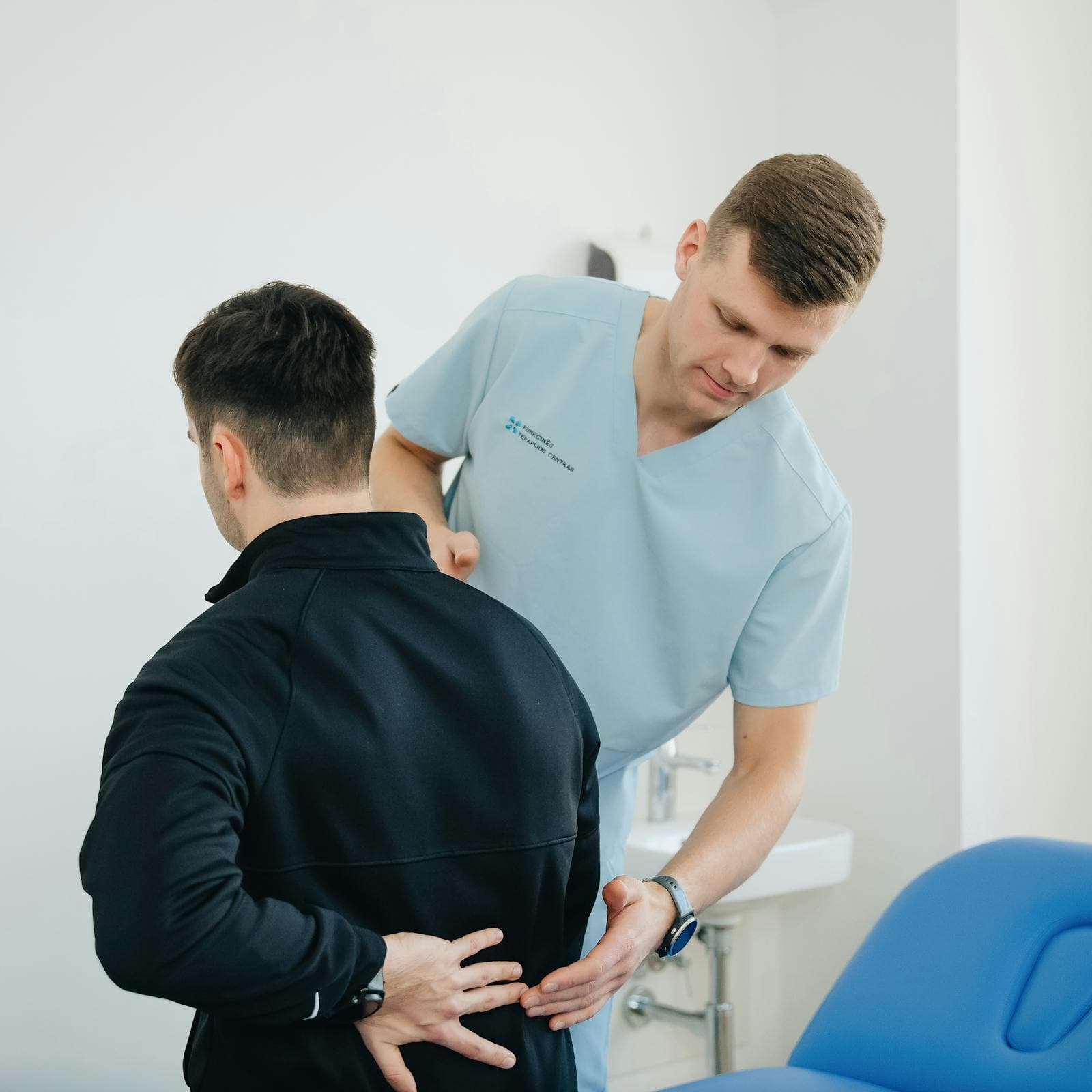 Profissional de saúde examinando a coluna de um paciente em consulta clínica